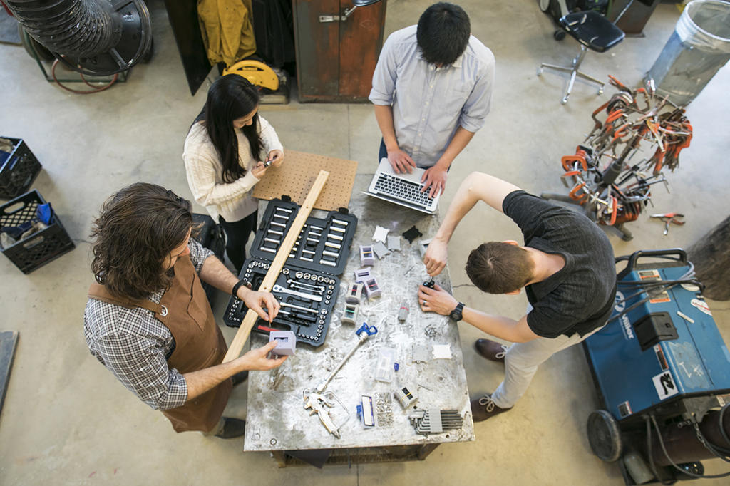 4 students work on a project around a worktable, photo from above